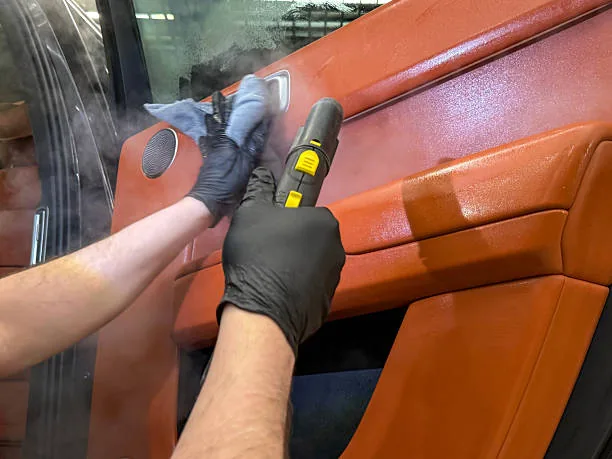 Technician steam cleaning an interior panel with a steam wand