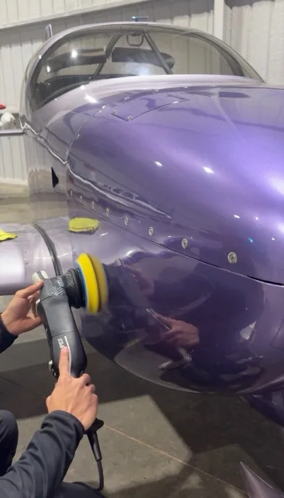 Technician machine polishing an aircraft fuselage in a hangar