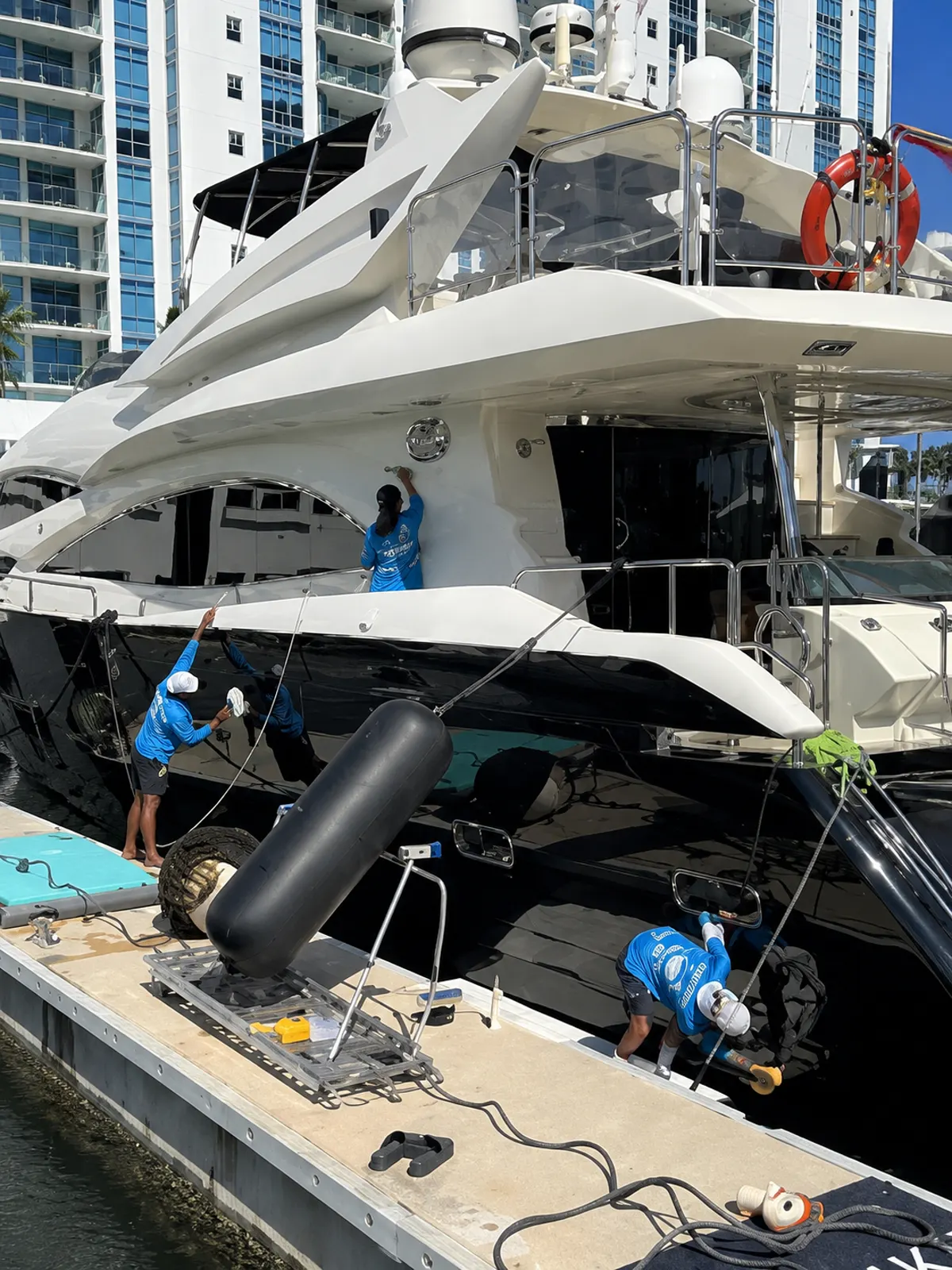 Detailing crew washing and detailing a yacht exterior dockside