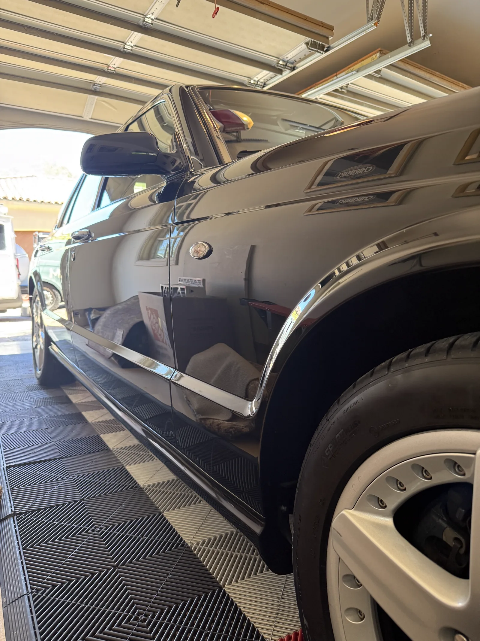 Reflective side profile of a black Bentley following paint correction and polishing