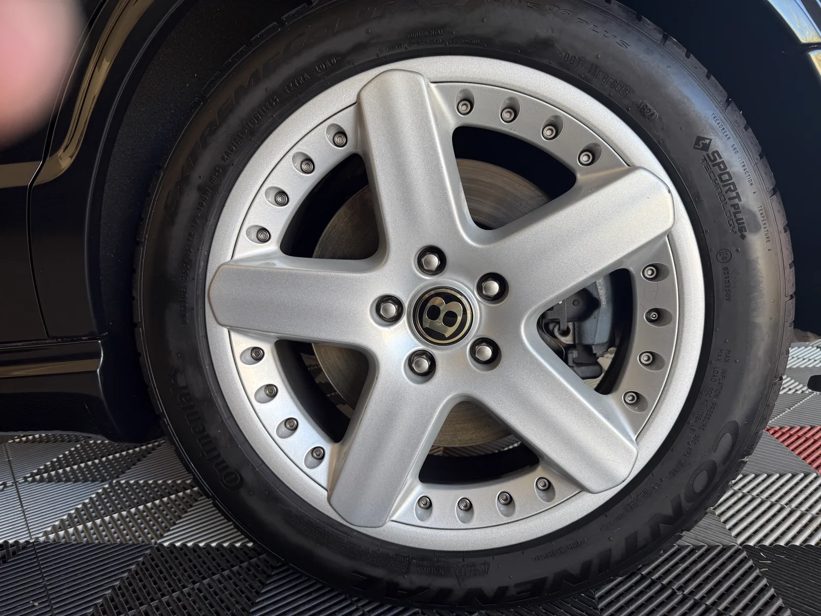 Close-up of a cleaned silver Bentley wheel and tire after detailing